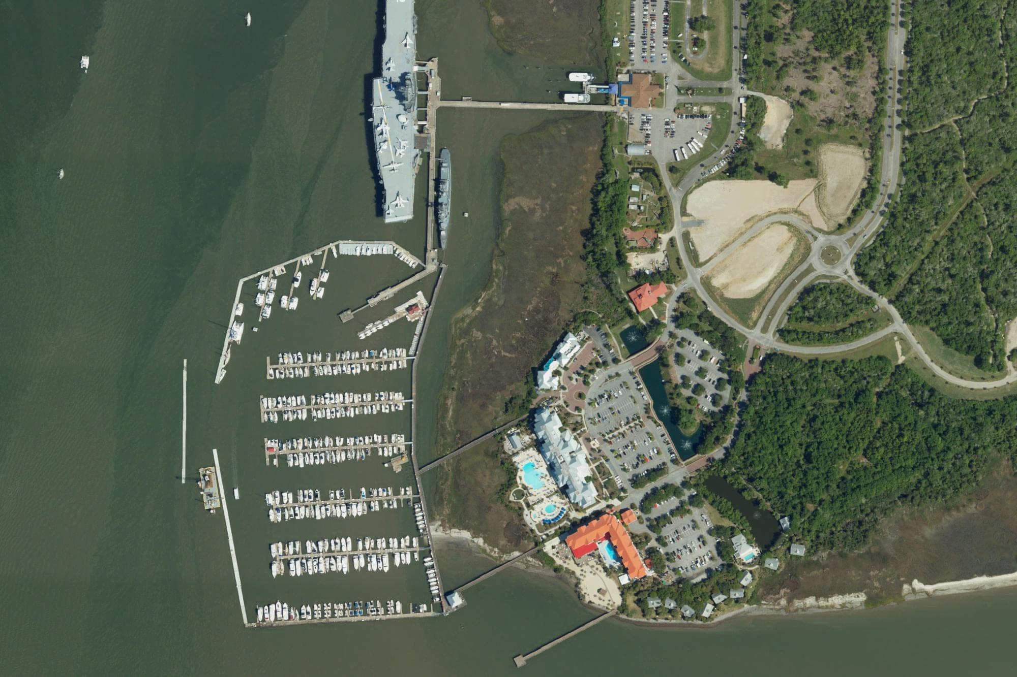 Charleston Harbor Resort & Marina at Patriots Point in Mount Pleasant, with the marina at left and the resort's hotels and pools at bottom center, in a U.S. Department of Agriculture aerial image from April 2023. The museum ship Yorktown is moored at top left.